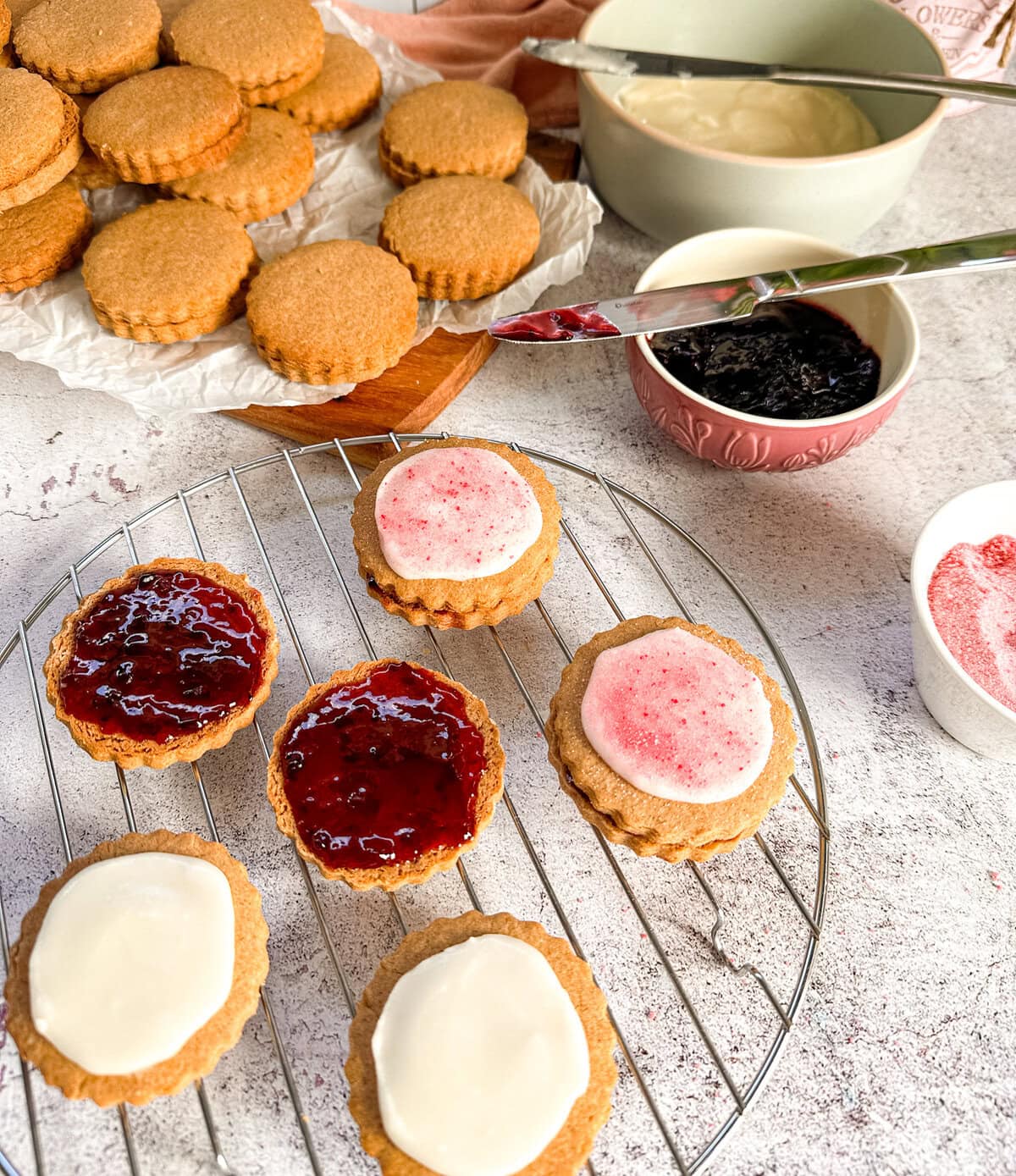 Preparing to sandwich together Belgium biscuits with jam, icing and jelly crystals