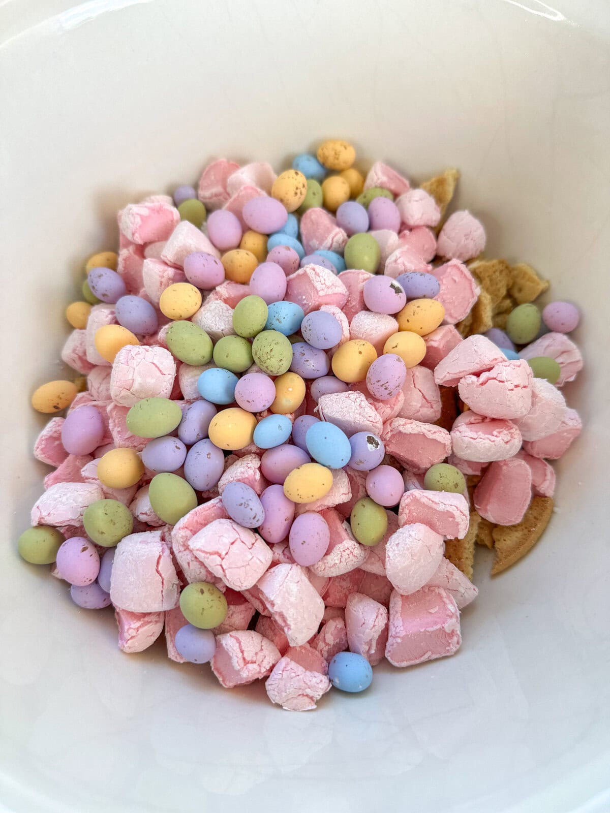 A large bowl with hard shell easter eggs pink marshmallows and biscuits, ready for melted chocolate. 