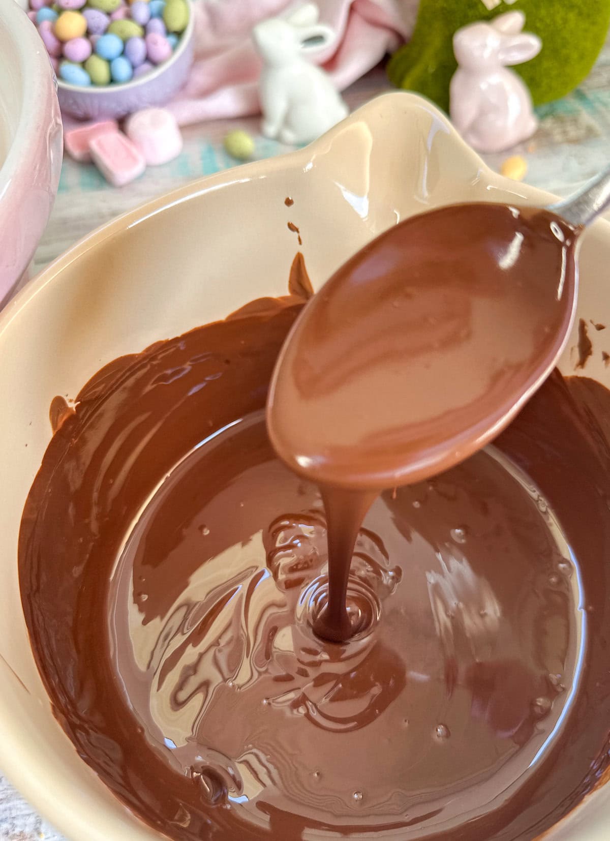 Melted dark and milk chocolate drizzling off the end of a spoon into a bowl. 