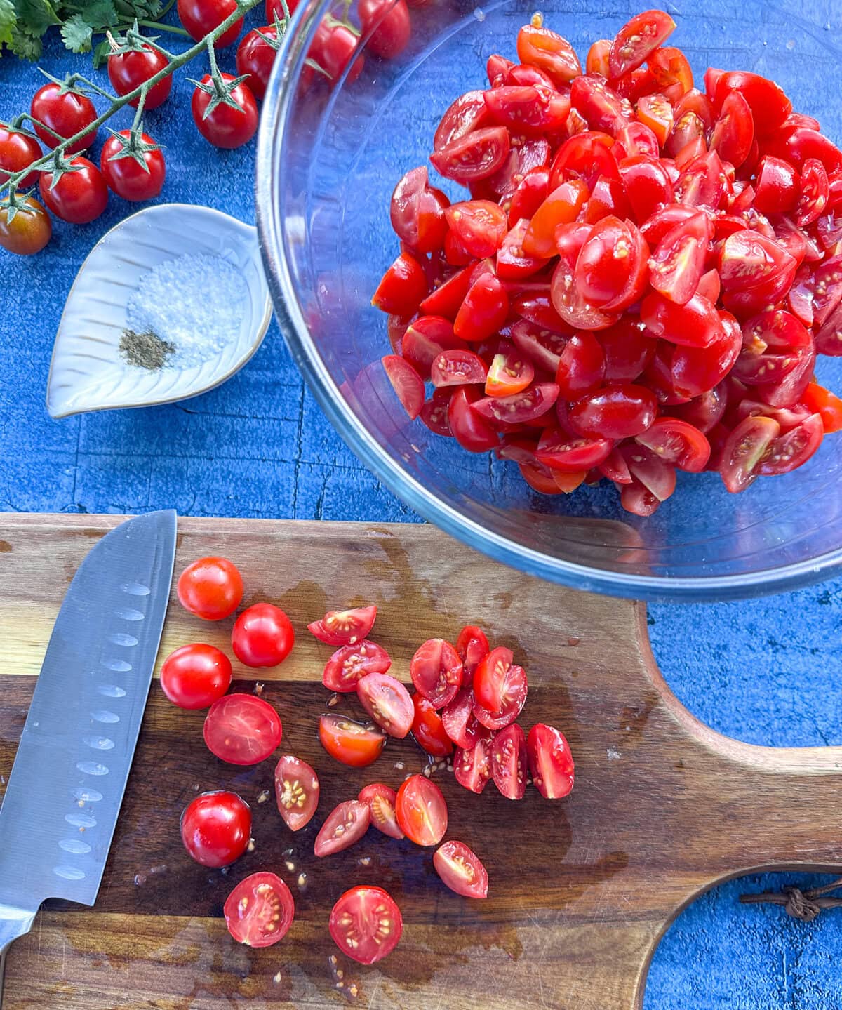 Cutting cherry tomatoes and adding them to a glass bowl