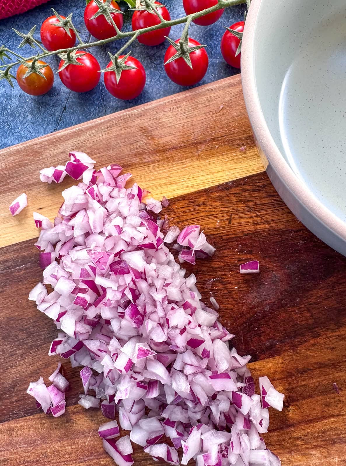 Finely diced red onion on a wooden cutting board