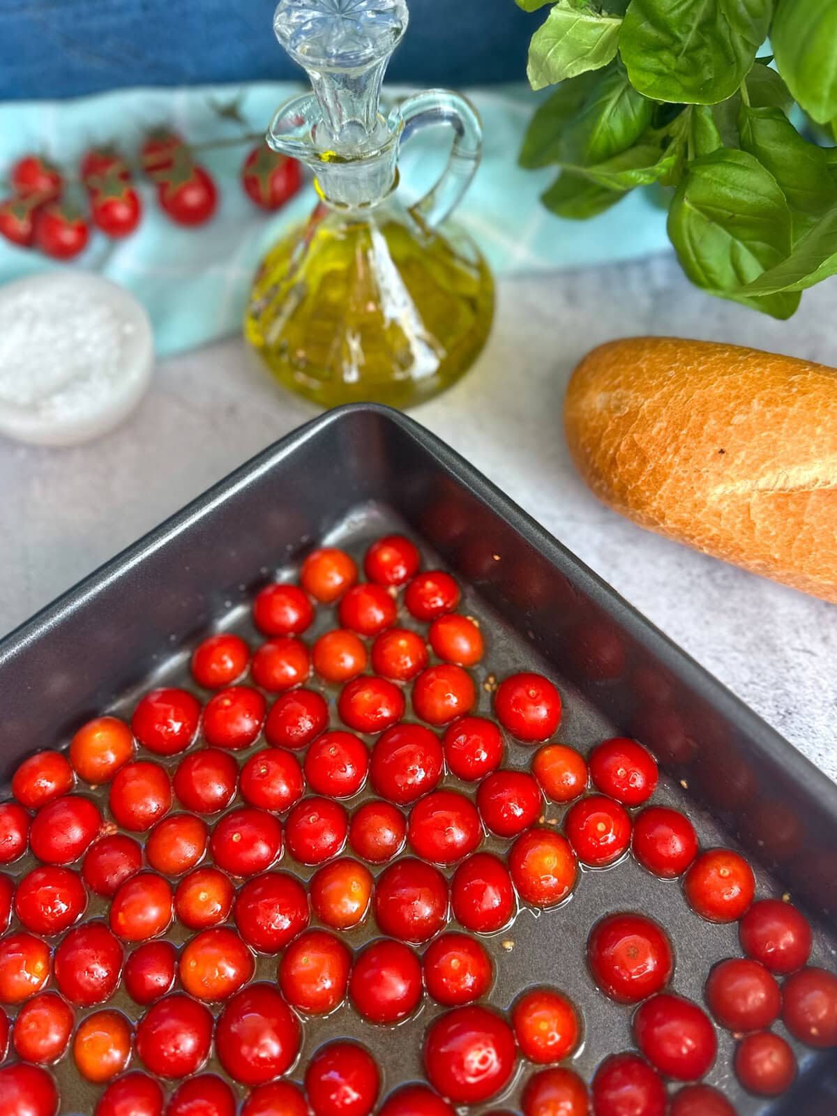 halved cherry tomatoes in a roasting dish ready for the oven, drizzled in olive oil