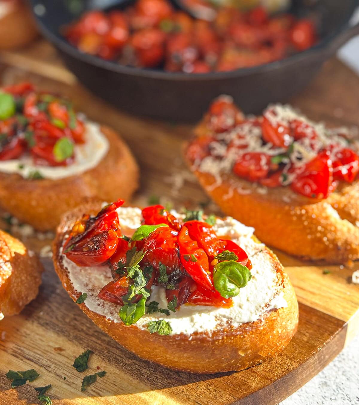 whipped feta spread on golden bruschetta with roasted cherry tomatoes and basil