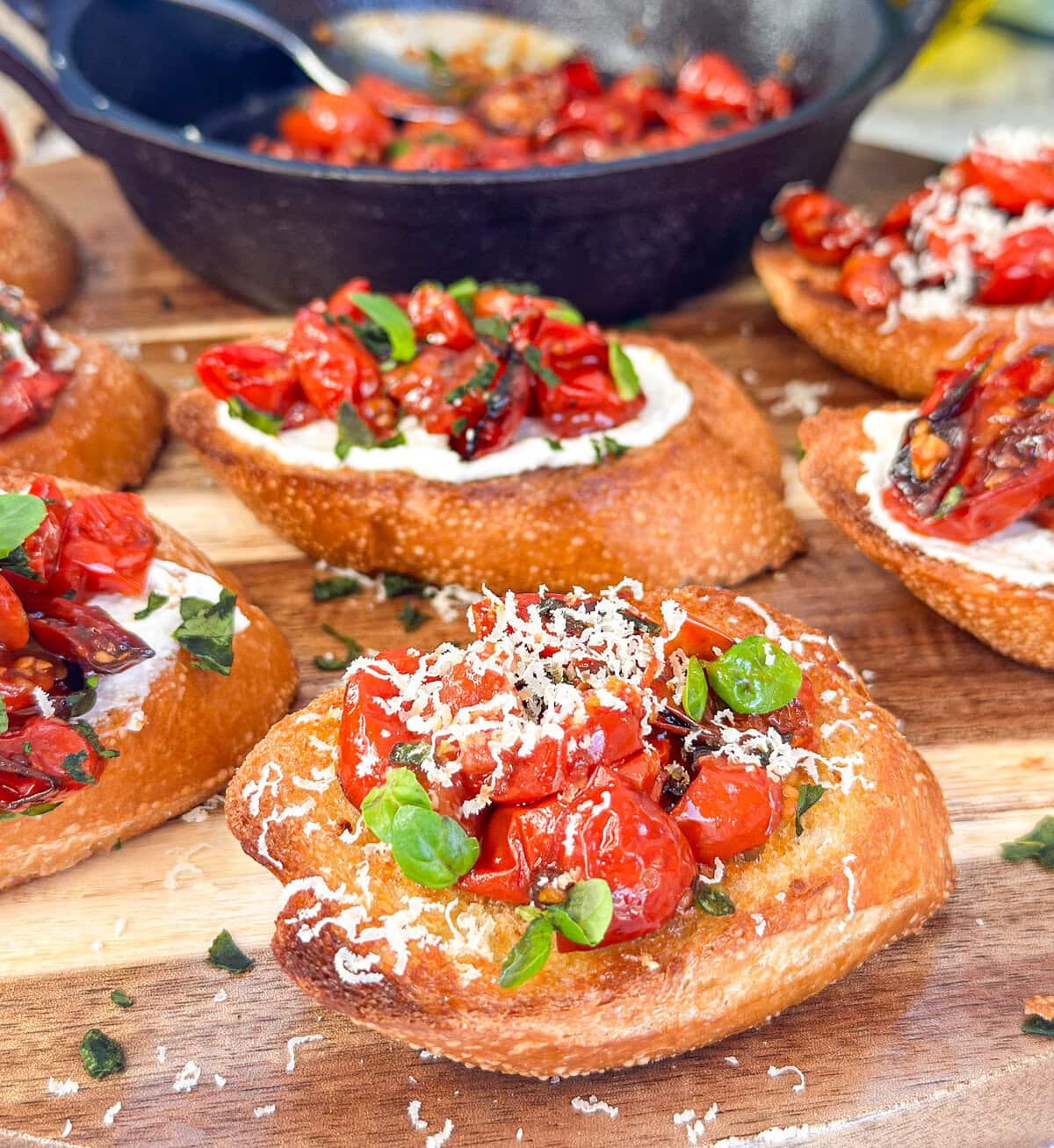 roasted cherry tomatoes, basil and parmesan on crusty golden bruschetta on a wooden serving board