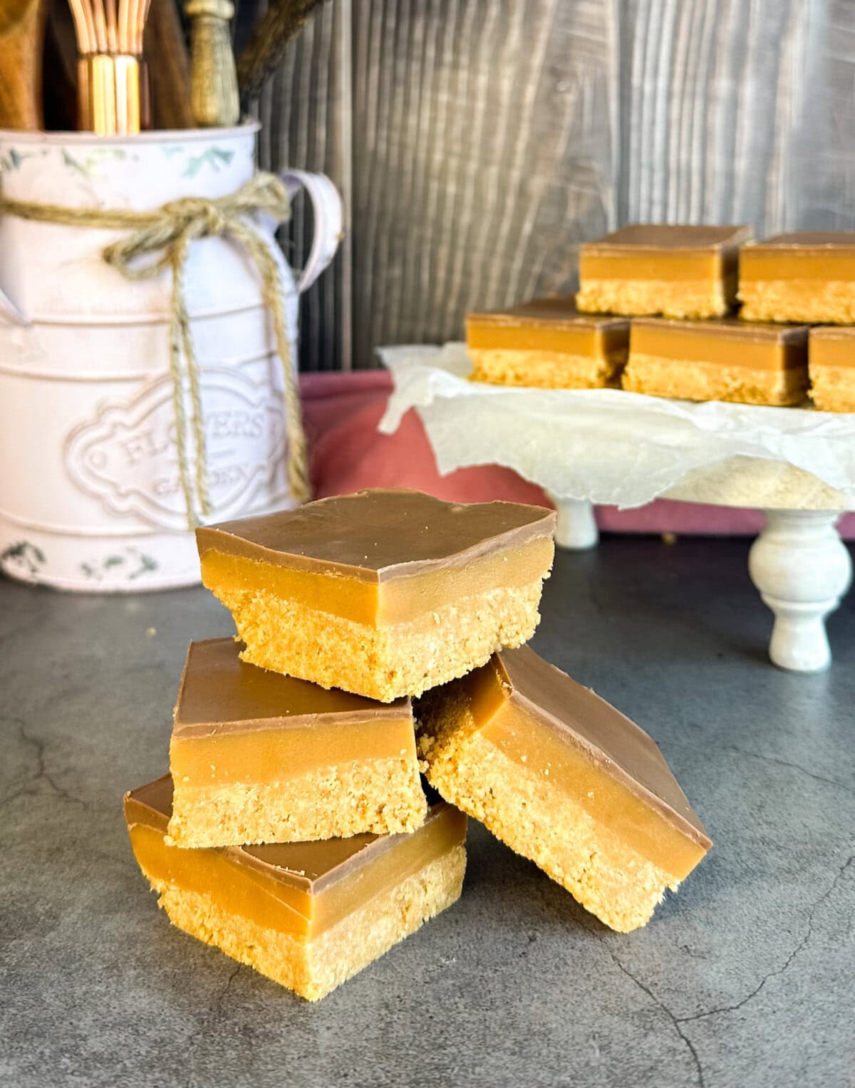 Stack of no bake caramel slice in the foreground and platter of slice in the background