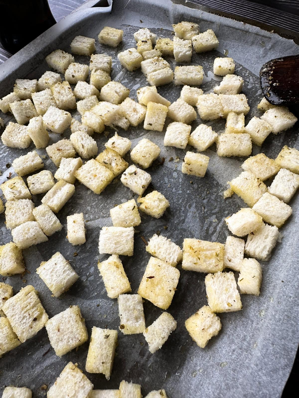 cubes of bread coated in oil and herbs ready to bake in the oven