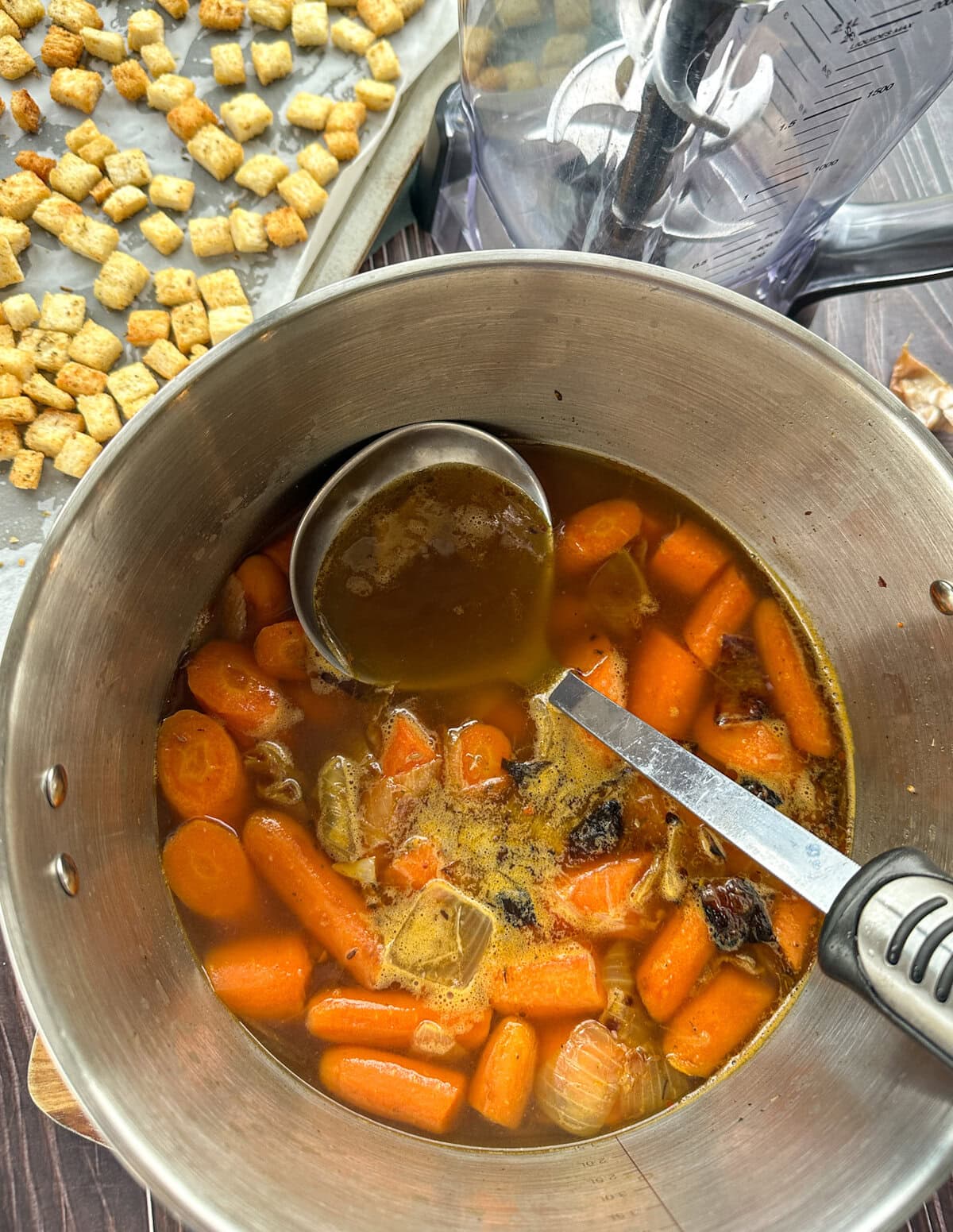 large saucepan with roasted carrots, onion and garlic to make soup with chicken stock