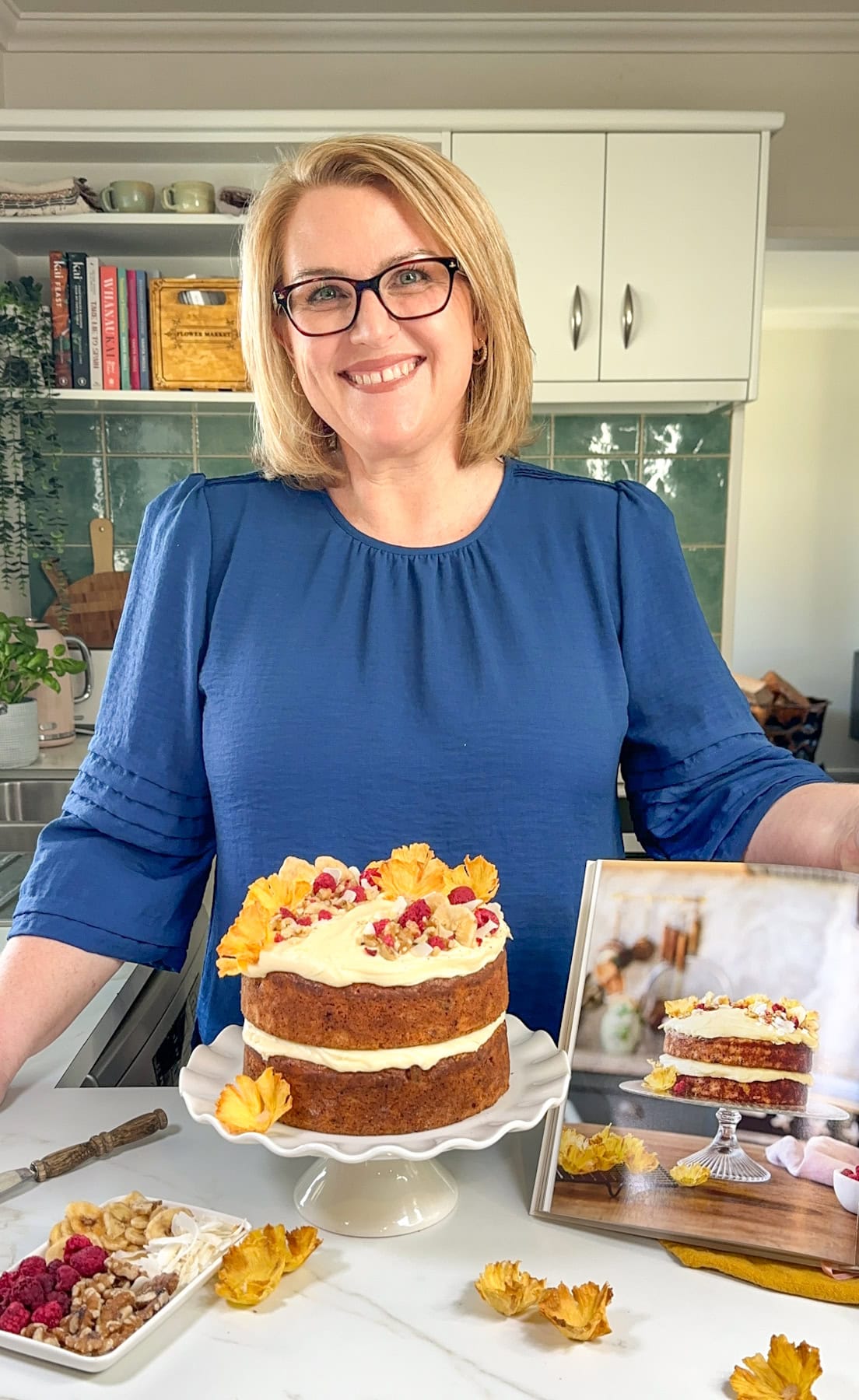 Anna from Just A Mum's Kitchen with her cookbook and a hummingbird cake 