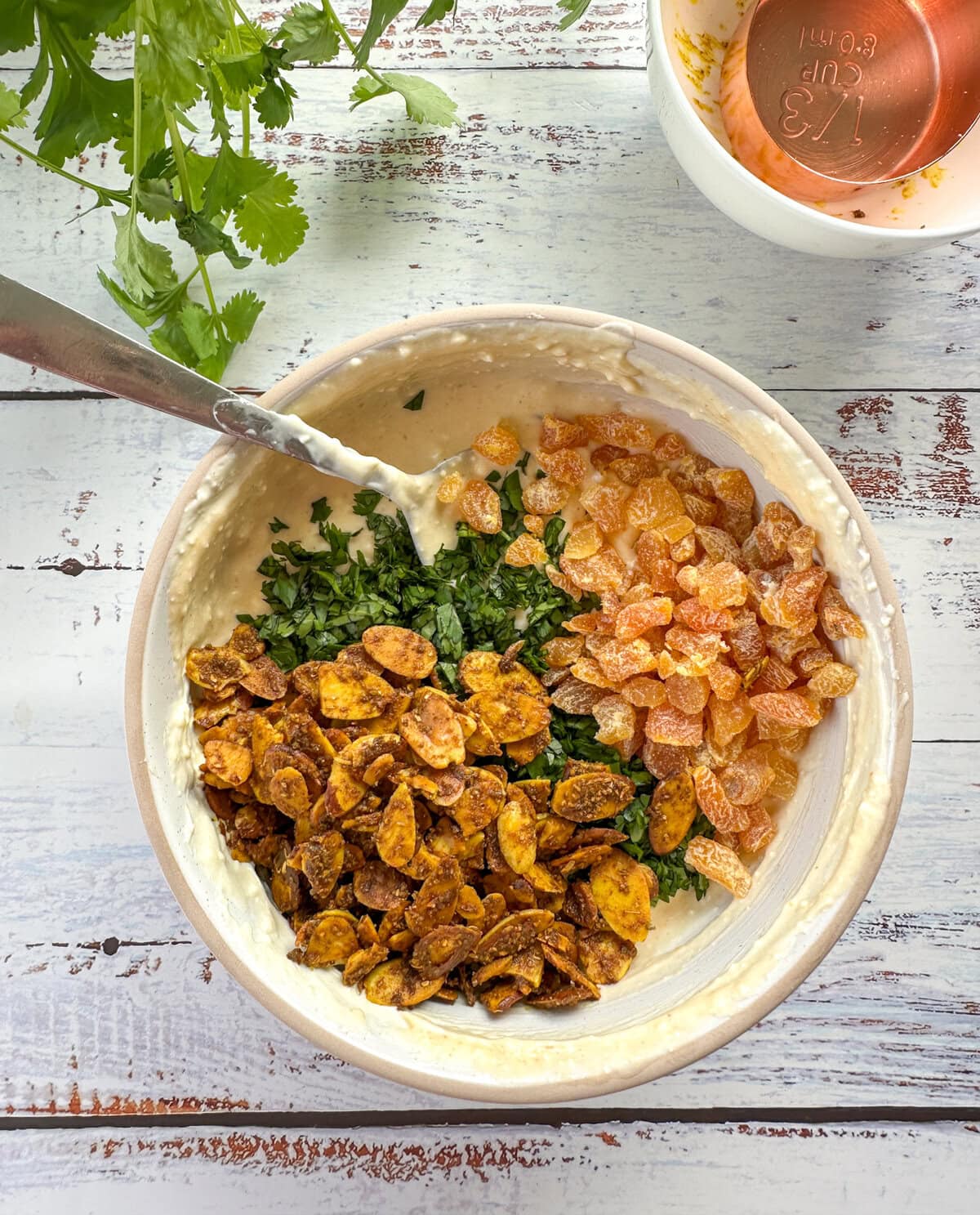 Adding the toasted almonds, curry, apricots, coriander to the creamy sauce for coronation chicken 