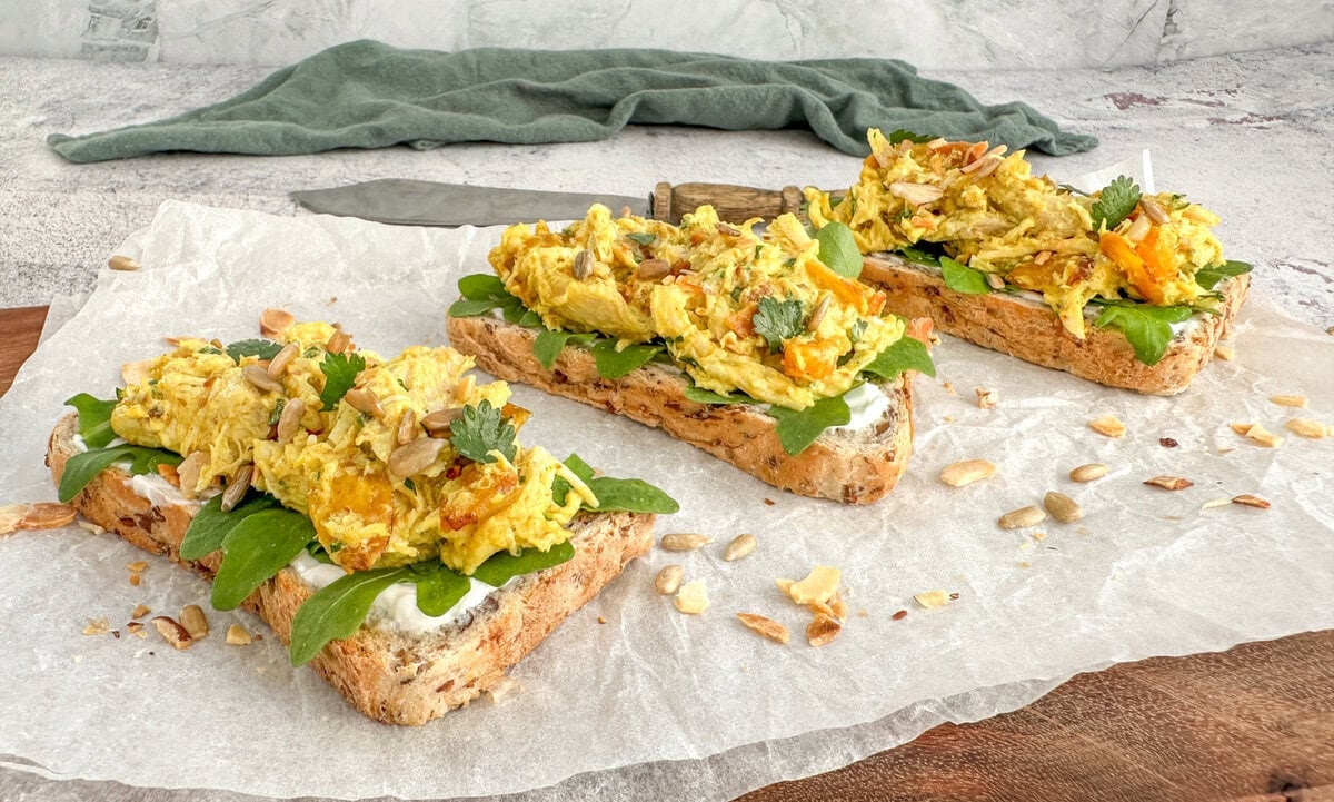 Coronation chicken served as an open sandwich on toasted bread with rocket and mayo