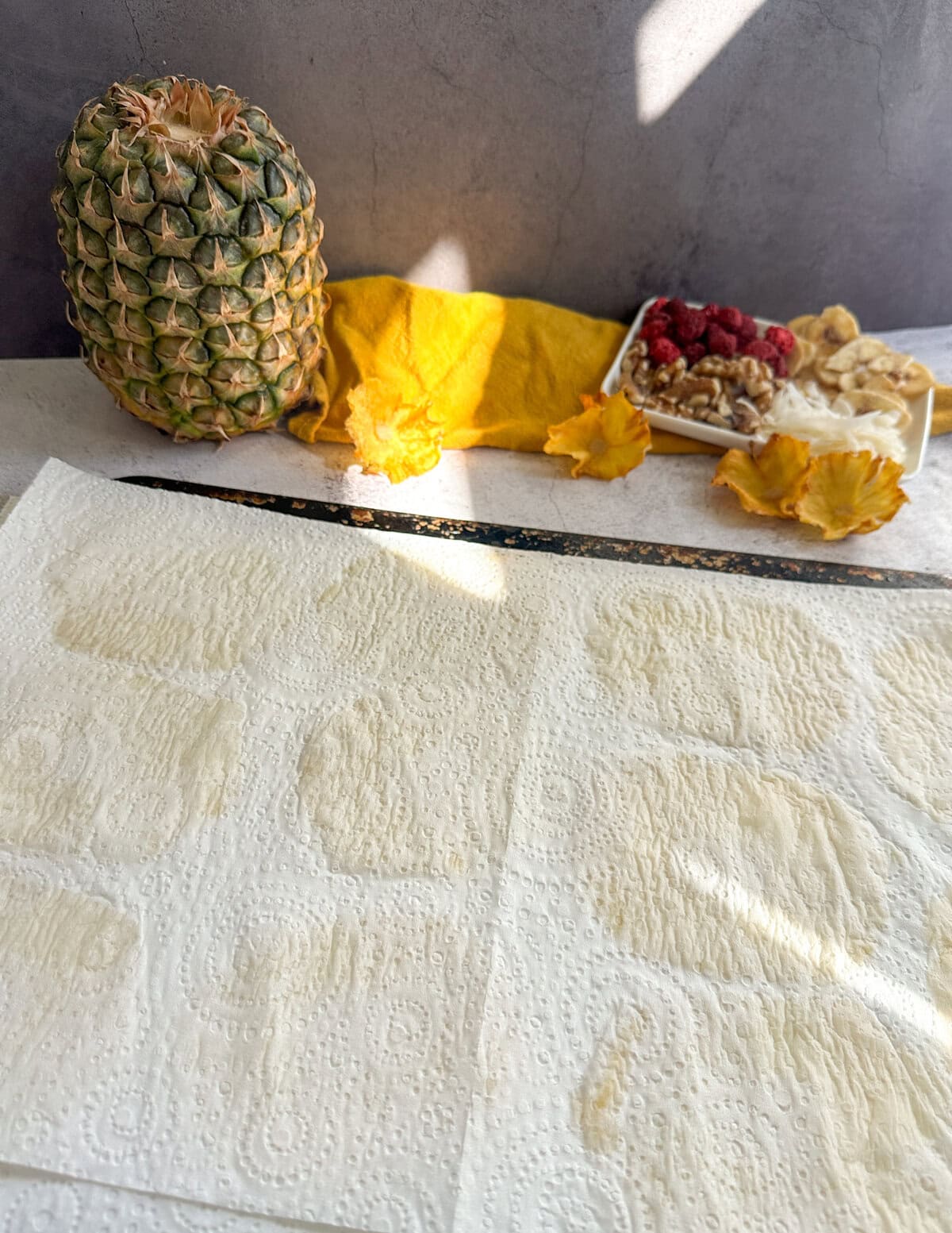 Paper towels placed over pineapple slices to dry them before baking 