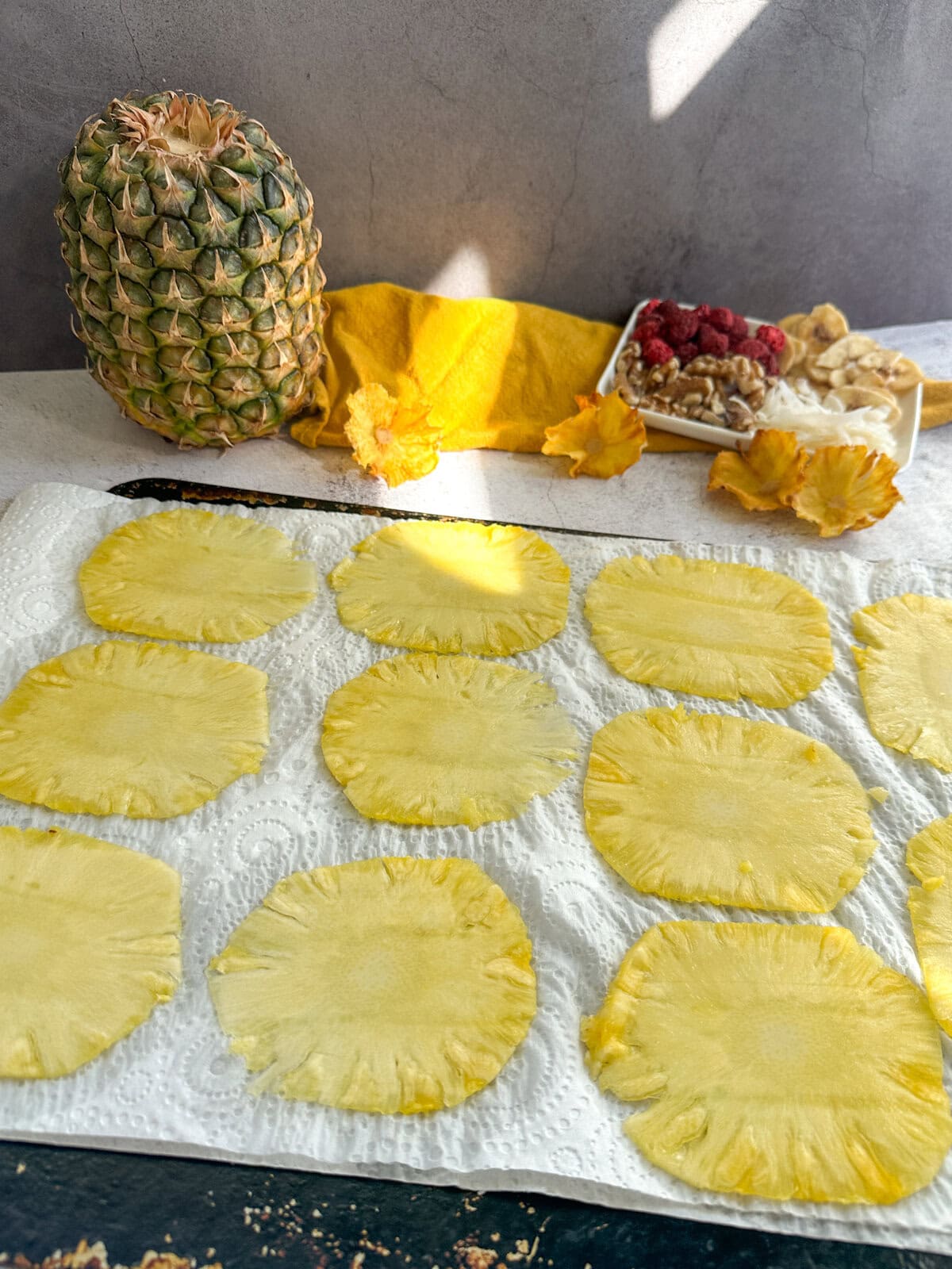 Thinly sliced pieces of pineapple on paper towels to make dried pineapple flowers 