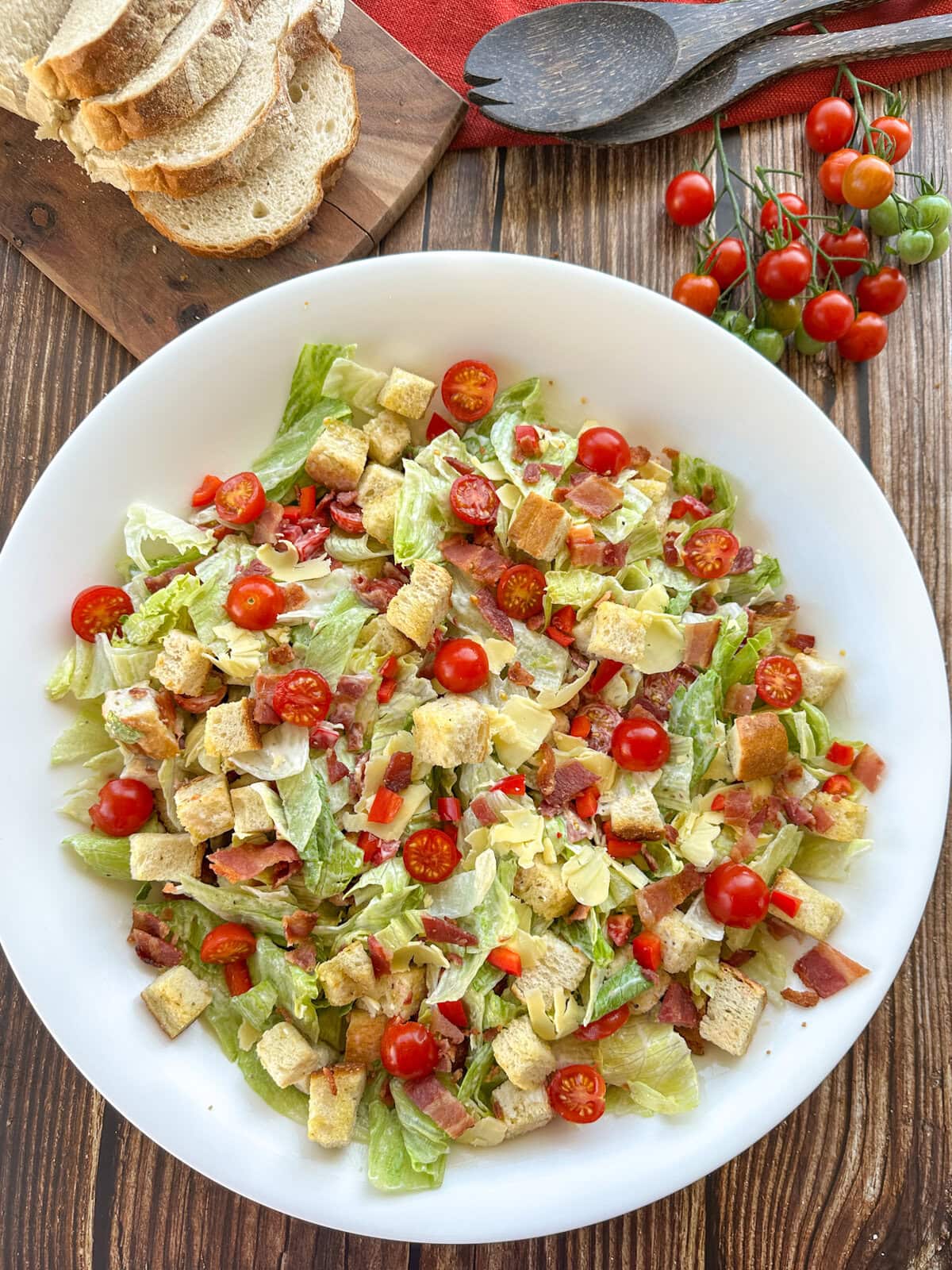 Mixed BLT Salad in a white bowl with bread and cherry tomatoes