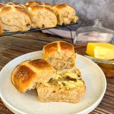plate with a cut open hot cross bun smeared with butter