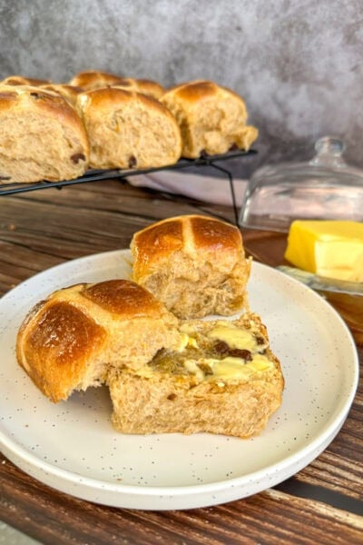 plate with a cut open hot cross bun smeared with butter