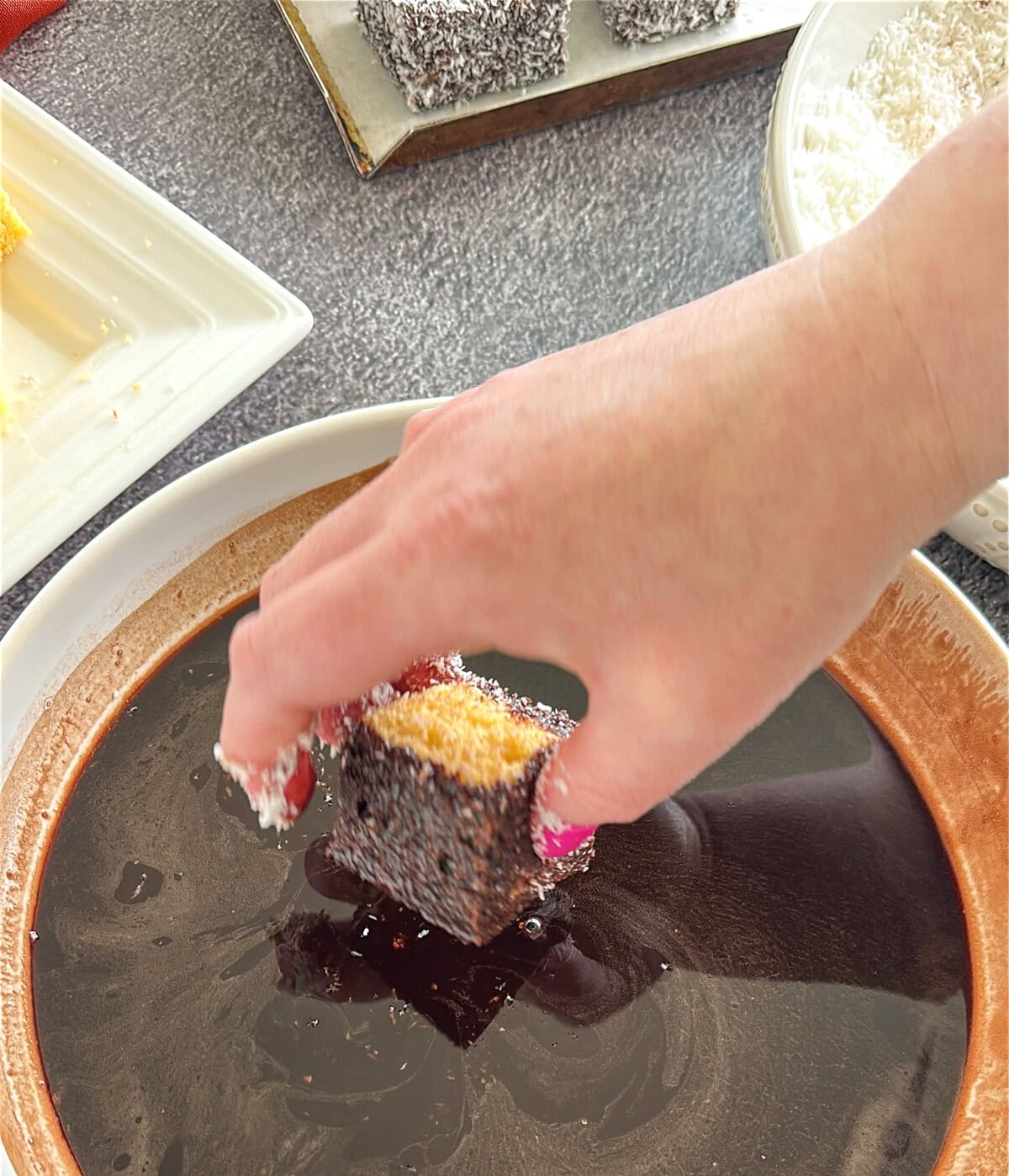 dipping the lamington in the chocolate syrup