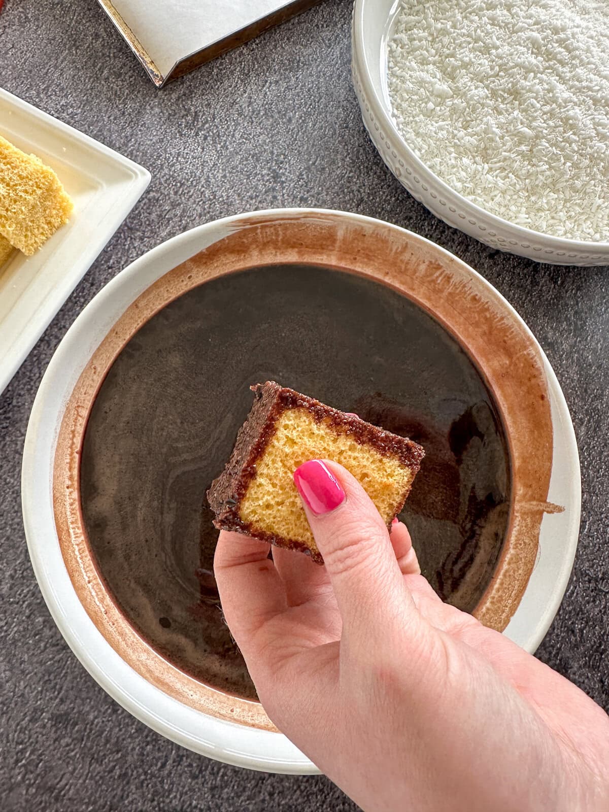 Coating chocolate Lamingtons with chocolate syrup
